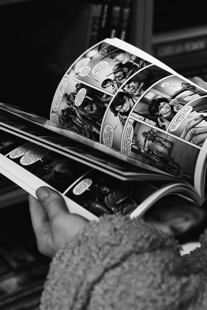 creative-01 Close-up of hands reading a black and white comic book, focus on the comic panels.