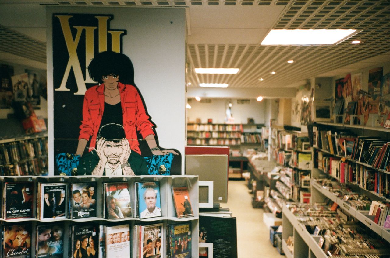Explore a cozy bookstore with vivid comic posters and diverse collections of books and DVDs.
