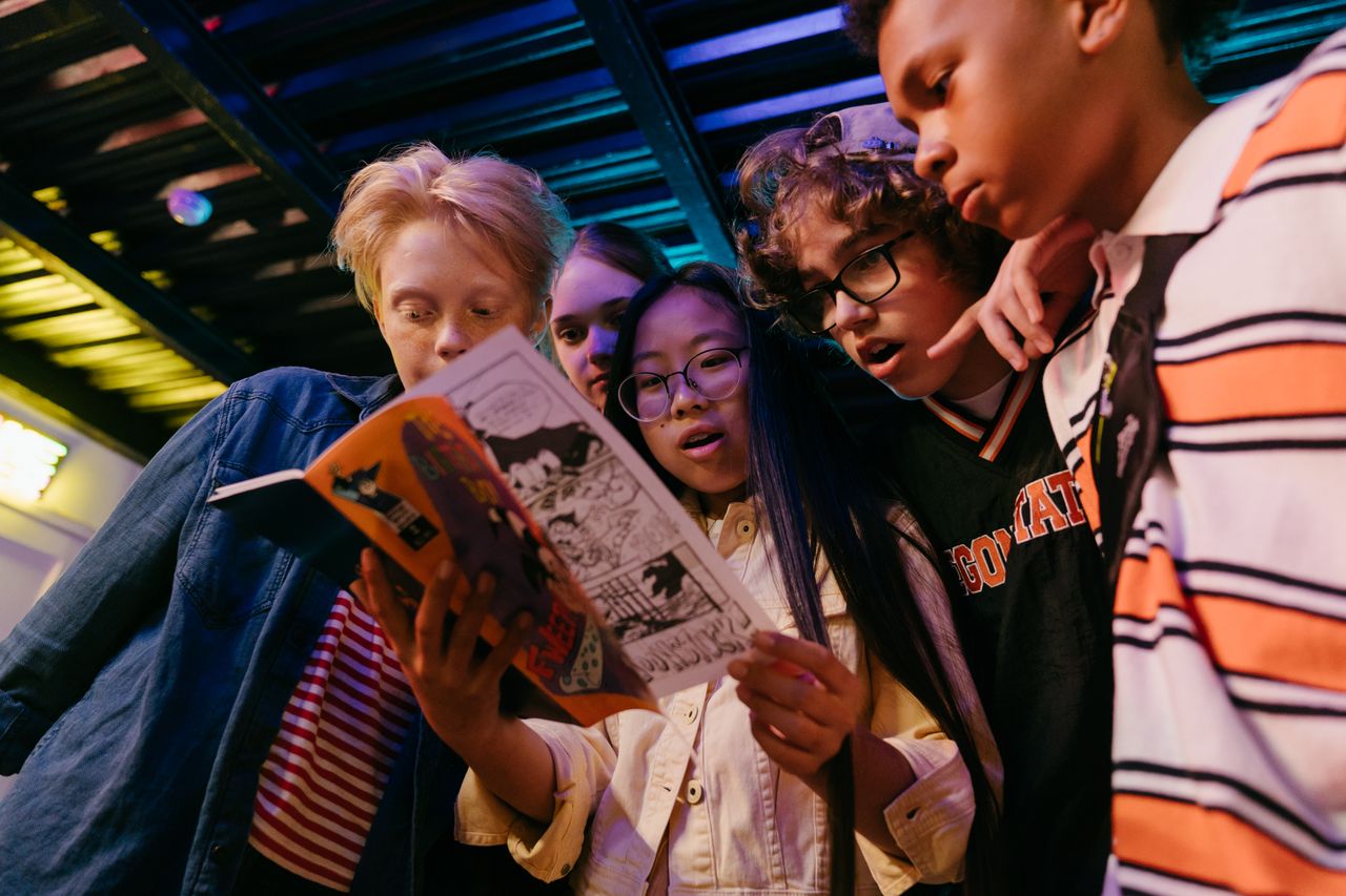 creative-03 Group of diverse teenagers reading a comic book indoors, showcasing friendship and excitement.
